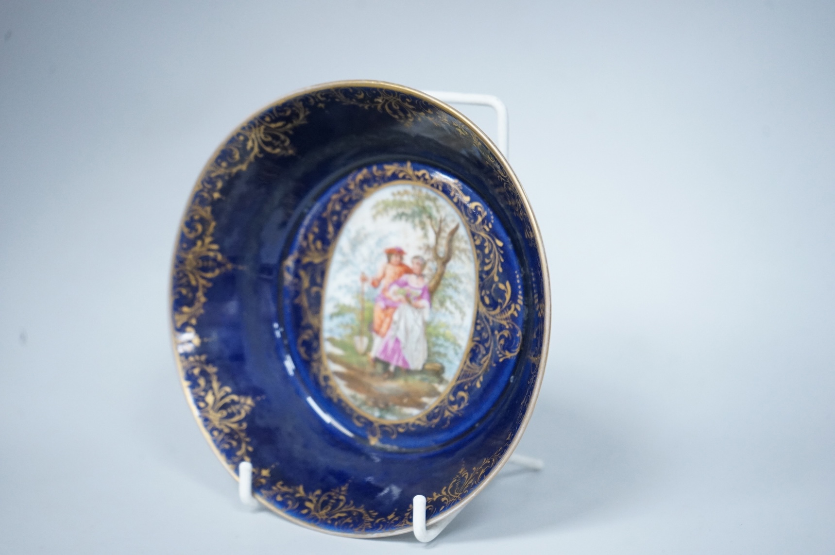 A 19th century Vienna saucer, hand painted with two figures beneath a tree, 15cm in diameter